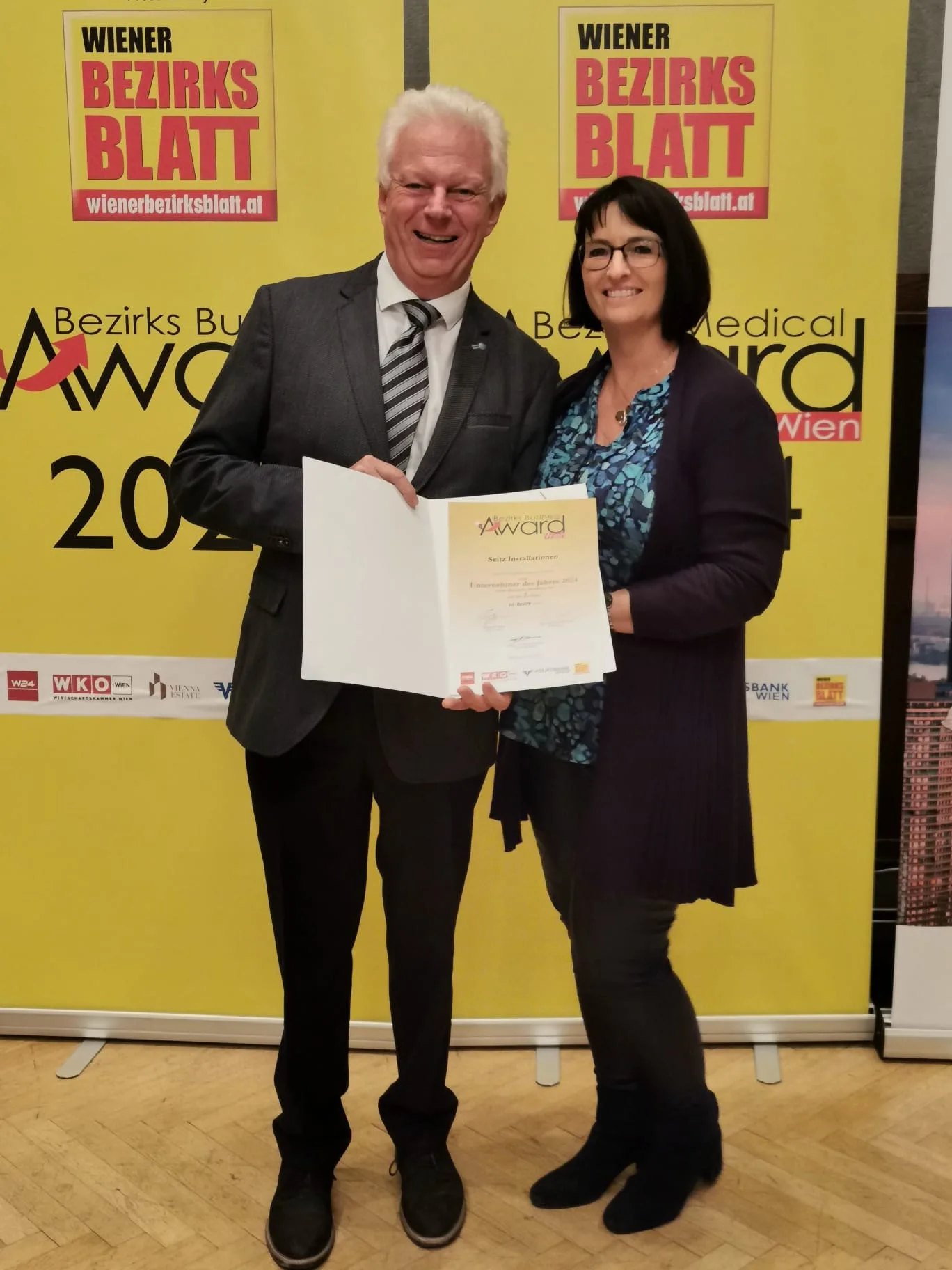Franz Seitz hält beim Bezirks Business Award des Wiener Bezirksblatts die Urkunde für Seitz Installationen, neben ihm eine Frau
